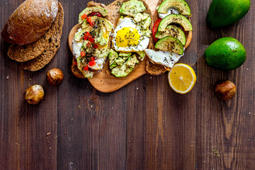Vegetarian breakfast. Sandwiches with avocado, fried eggs and paprika on wooden table top view copyspace