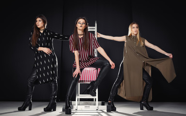Three stylish girls in fashionable images and with an unusual makeup on a dark background