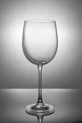 Empty wine glass standing on the table against a light spot