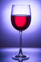 Beautiful glass with red wine up to the light in front of a blue light spot