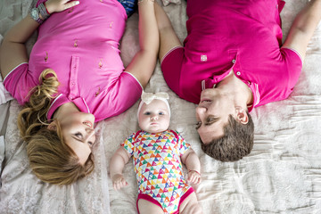 Happy family on the bed. Mom and Dad play with their little daughter