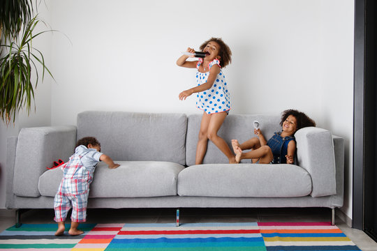 happy siblings playing wildly on sofa