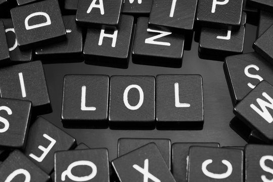 Black letter tiles spelling the word "lol" on a reflective background