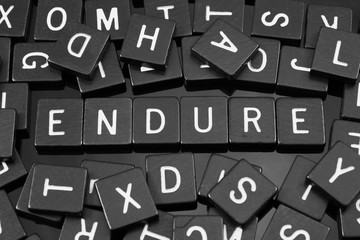 Black letter tiles spelling the word "endure" on a reflective background
