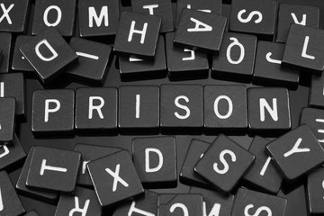 Black letter tiles spelling the word "prison" on a reflective background