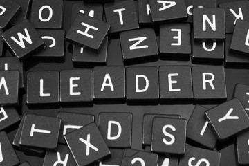 Black letter tiles spelling the word "leader" on a reflective background