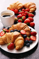 Delicious breakfast with fresh croissants and ripe berries on old marble background