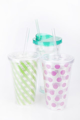 Green and pink plastic tumblers on a white surface. Tumblers isolated on white background.