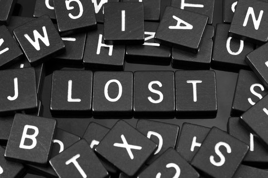 Black letter tiles spelling the word "lost" on a reflective background