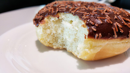 Bitten delicious donut on plate close-up