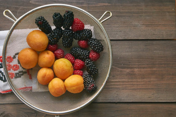 colander with the washed-up berries raspberry and blackberry and apricots