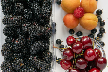 fresh tasty blackberry, cherry and apricots in a plastic transparent tray