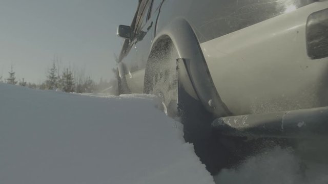 Driving SUV car in winter on forest road with much snow. Car stuck in the woods. Closeup