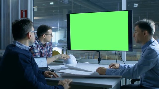 Team of Industrial Engineers Have Important Meeting. Presentation Display Shows Mock-up Green Screen. In the Background Factory is Seen. Shot on RED EPIC-W 8K Helium Cinema Camera.