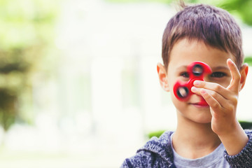 Boy with a fidget spinner outdoors - obrazy, fototapety, plakaty