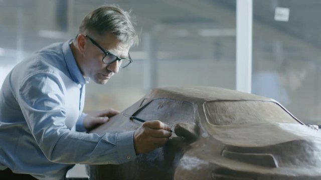 Chief Automotive Designer with Rake Sculpts Futuristic  Car Model from Plasticine Clay. He Works in a Special Studio Located In a Large Car Factory.Shot on RED EPIC-W 8K Helium Cinema Camera.
