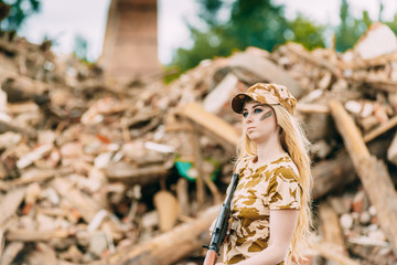 Portrait of a beautiful girl in yellow camouflage and a cap with a gun in her hands