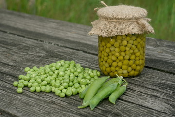 Green peas canned in a glass jar on a wooden table