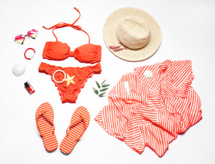 Red bikini and beach accessories on white background
