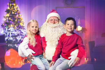 Authentic Santa Claus with little children at home. Christmas and New Year celebration