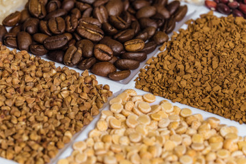 Set of groceries laying horizontal perspective with limited depth of field: roasted coffee beans, freeze-dried instant coffee, buckwheat, dried peas.v
