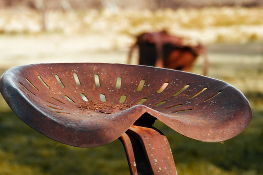 Rusty seat of an abandoned plow on a farm