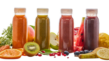 Selection of different energising fruit smoothies in four bottles surrounded by fresh ingredients with pear, orange, watermelon, pomegranate, kiwi, mango, carrot and apple on white for a healthy diet