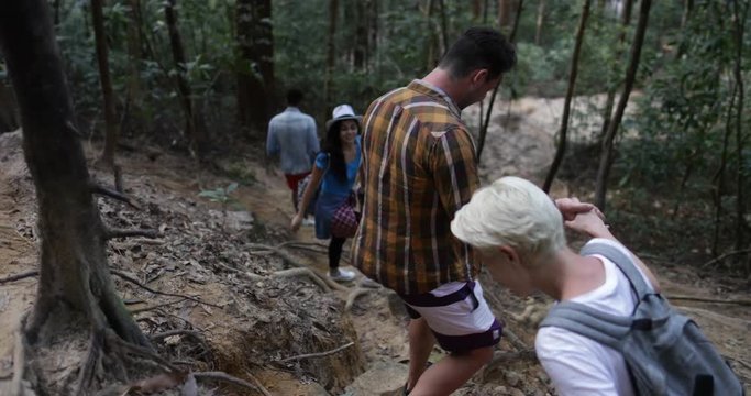 Group Of People Help Each Other To Walk Donwhill In Forest, Team Of Young Tourists On Hike Together Slow Motion 60