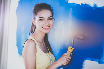 Beautiful young woman doing wall painting , standing