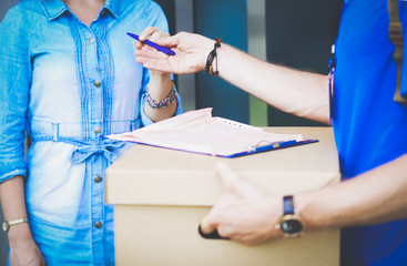 Smiling delivery man in blue uniform delivering parcel box to recipient - courier service concept