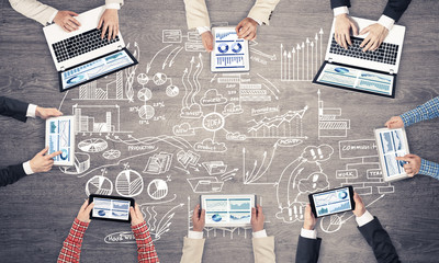 Top view of businesspeople sitting at table and using gadgets