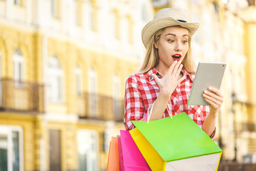 Obraz premium Portrait of young happy smiling woman with shopping bags. Online shopping. With tablet.