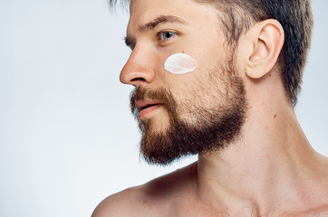 Young guy with beard on white isolated background, face cream