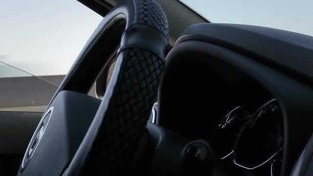 A fake driverless car, apparently no hands on the steering wheel. Detail shot, seen from the front passenger's seat.
