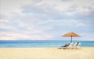 Fototapeta na wymiar Beach background with lovers on beach chairs