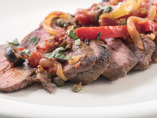 Close up of sliced sirloin steak with vegetables & sauce