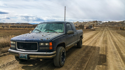 Older Chevy Silverado GMC Sierra Pickup Truck K1500 Off Road in Country side of Wyoming while covered in Mud - obrazy, fototapety, plakaty