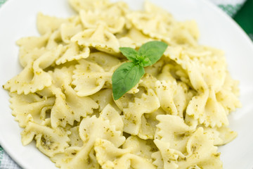 Farfalle pasta with pesto genovese (basil sauce) on rustic wooden table. Italian cuisine