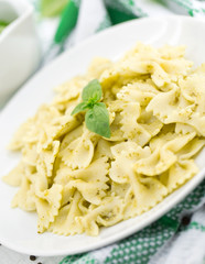  Farfalle pasta with pesto genovese (basil sauce) on rustic wooden table. Italian cuisine