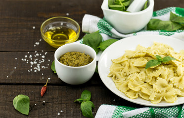  Farfalle pasta with pesto genovese (basil sauce) on rustic wooden table. Italian cuisine.  Flat lay. Top view.