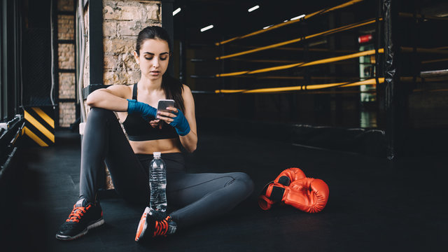 Young woman sitting on the floor after hard workout in gym.