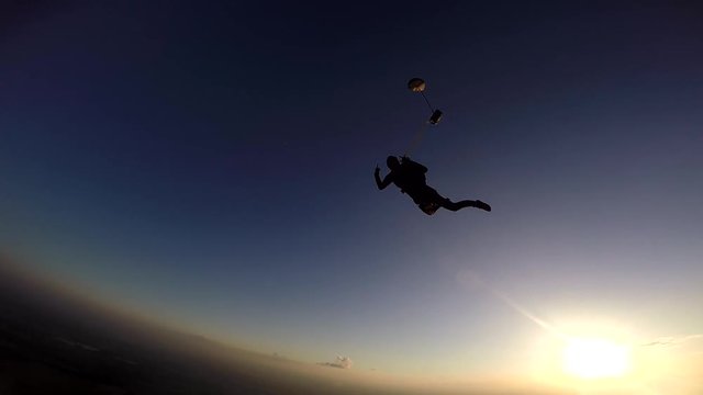 Parachutist opening the parachute at sunset