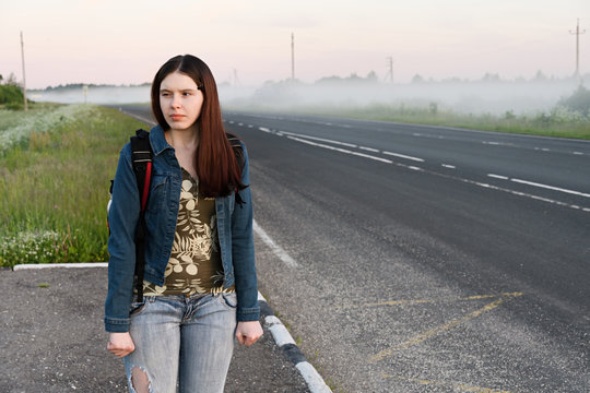 An angry young woman traveler, waiting for late transport on the side of the road.