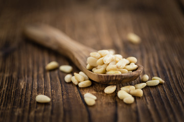 Portion of Pine Nuts on wooden background (selective focus)