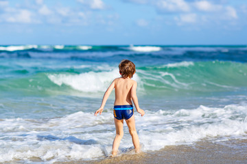 Fototapeta na wymiar little blond kid boy having fun on ocean beach in Florida