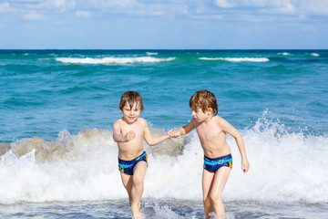 Two kid boys running on ocean beach in Florida