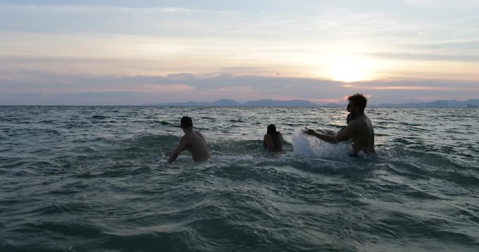 Group Of Friends Splashing In Sea At Sunset, Cheerful People Young Swimming On Beach Together During Summer Vacation Slow Motion 60