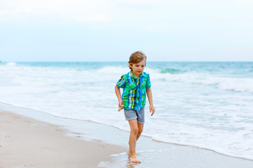 Fototapeta na wymiar little kid boy running on the beach of ocean