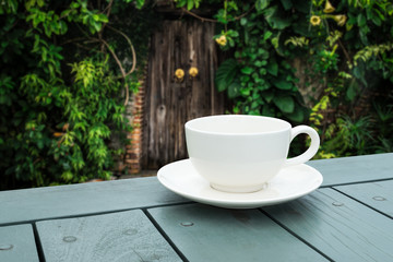 White coffee cup on table in the green park.