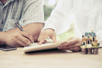 Real estate concept - businessman signs contract behind home arc